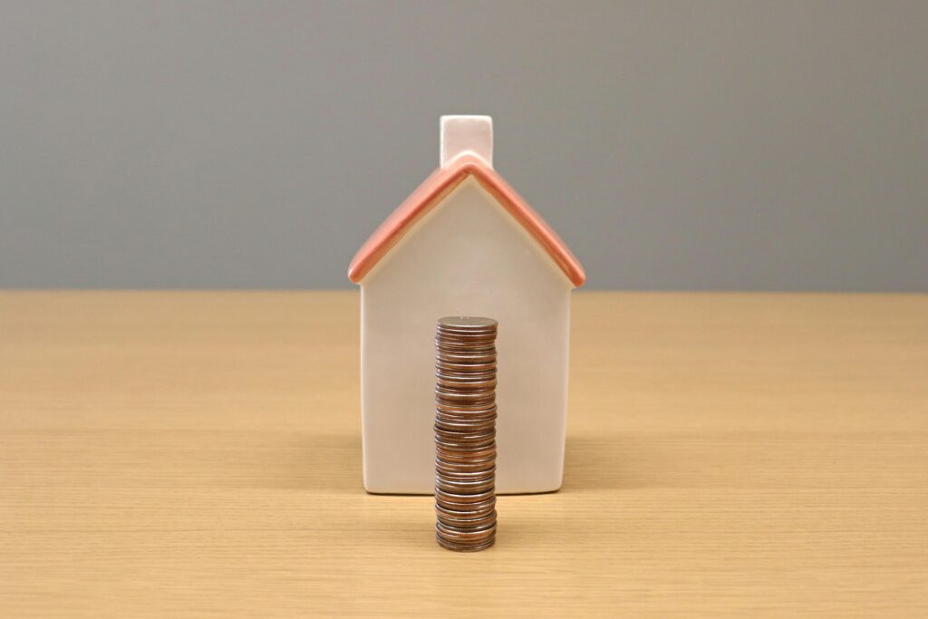 Stack of Coins in Front of a Porcelain House