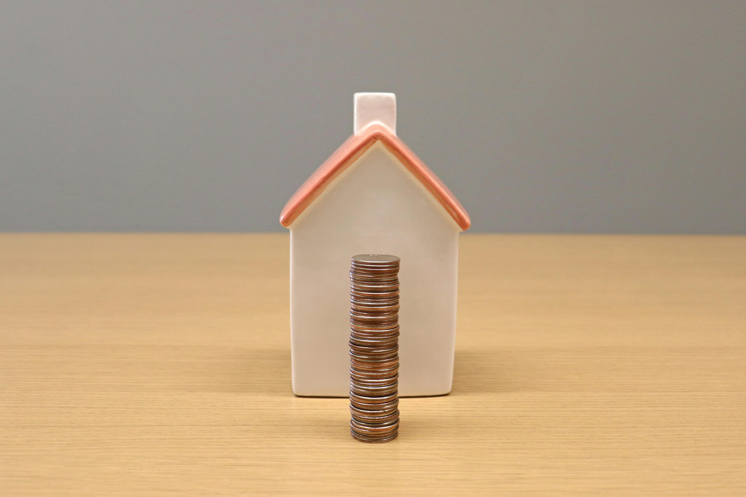 Stack of Coins in Front of a Porcelain House